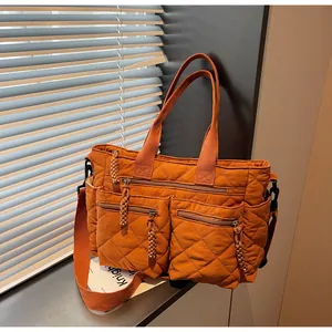 Detail der orangefarbenen gesteppten Nylontasche mit mehreren Taschen und Schultergurt