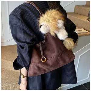 Detail of brown suede tote bag featuring a plush lion charm and golden ring buckle accents