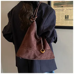 Close-up of brown suede tote bag featuring gold ring charm and white contrast stitching