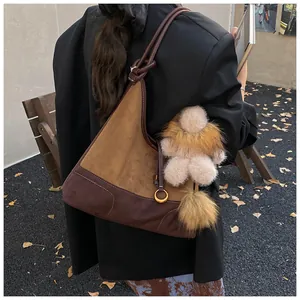 Detail of suede patchwork tote bag with knot strap and plush accessories in street style