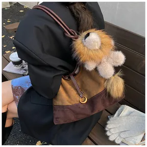 Close-up of suede patchwork tote bag with gold ring buckle and plush lion pendant