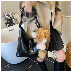Chic black hobo bag in faux leather featuring a large plush pompom charm and long straps