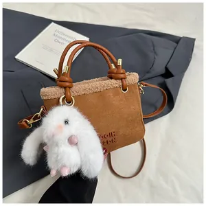Détail du sac seau en daim marron avec garniture en peau lainée et breloque lapin blanc