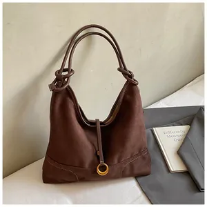 Close-up of brown faux suede hobo bag featuring a decorative knot and golden hardware