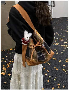 Detail view of plaid patchwork bucket bag with drawstring and cute plush charm detail