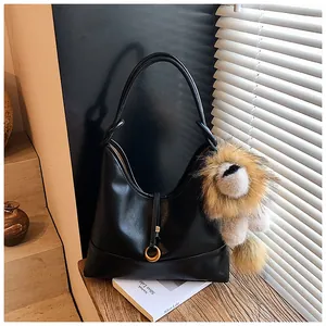 Close-up of black suede tote bag featuring a gold ring clasp and a lion plush pendant