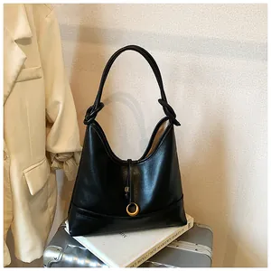 Detail of minimalist black hobo bag featuring knotted shoulder strap and golden ring charm