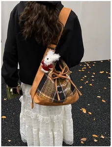 Brown plaid tote bag with wide strap and cute plush bear charm on autumn street