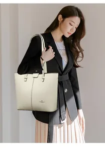 Close-up of beige lychee texture leather tote with metallic buckle and logo detail