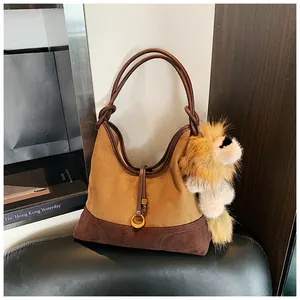 Detail of hobo bag with suede finish, buckle strap and plush lion charm on shelf