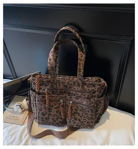 Detail of leopard print corduroy tote bag showing dual front zipper pockets and texture