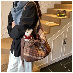 Detail of wool tote bag with plaid pattern, drawstring bow, and cute bear pendant