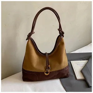 Close-up of suede shoulder bag with caramel and brown colors and golden ring detail
