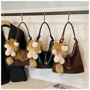 Detailed view of three suede shoulder bags with plush lion charms and metal ring buckles