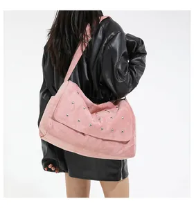 Sac à bandoulière rose style daim avec rivets argentés et large sangle sur une veste en cuir