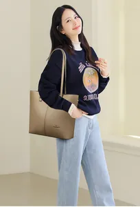 Close-up of litchi grain tote bag showing brand logo and leather texture on a khaki model