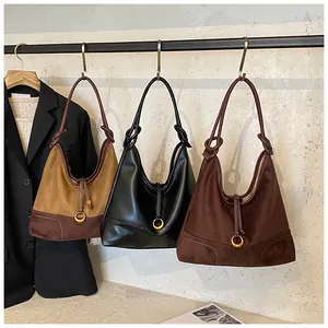 Detailed view of three suede and leather hobo shoulder bags in brown, black, and coffee