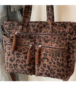 Detail of leopard print corduroy tote bag featuring three front zip pockets and woven pulls