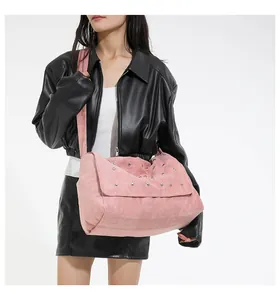 Sac bandoulière en daim rose avec rivets argentés et texture plissée sur mannequin femme