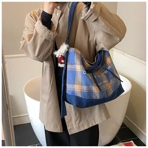 Detail view of plaid canvas tote bag with lettering and cute plush doll accessory