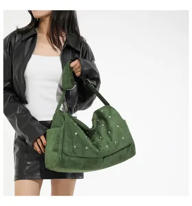 Détail du sac à bandoulière en daim vert avec clous argentés et plis élégants