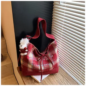 Detail of red plaid canvas tote bag featuring a cute teddy bear charm and drawstring bow