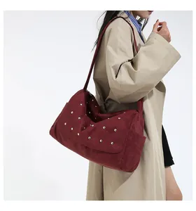 Détail du sac hobo en daim bordeaux avec clous argentés et rabat de fermeture