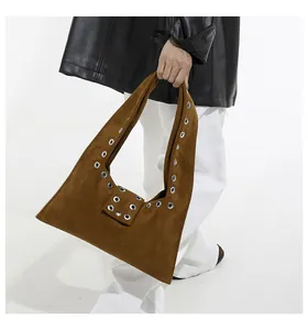 Macro detail of brown suede hobo bag with silver metallic grommet studs on the strap