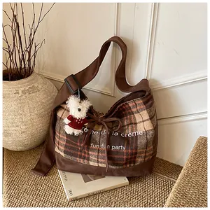Detail of plaid canvas tote with creme de la creme text and cute bear charm pendant