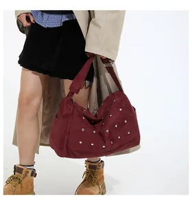 Détail du sac à bandoulière bordeaux avec rivets argentés et sangle ajustable