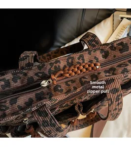 Detail of smooth metal zipper and brown woven pull on leopard print corduroy tote bag