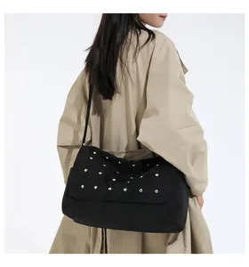 Détail du sac à bandoulière noir à rivets sur un mannequin portant un trench-coat kaki