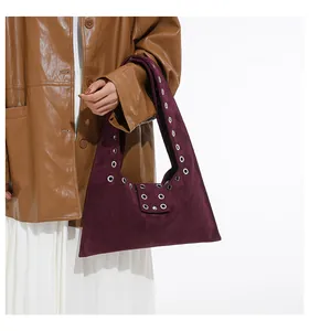 Close-up of rivets and grommets on a deep purple suede leather tote shoulder bag