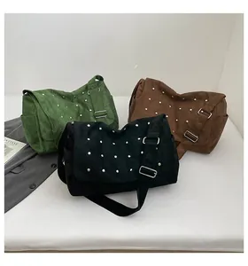Détail des sacs bandoulière en daim en vert, noir et marron avec des clous argentés
