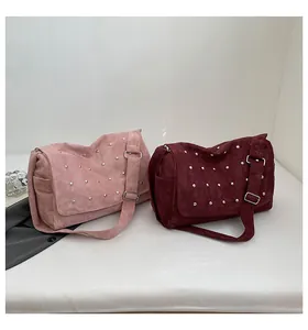 Détail de sacs à bandoulière en daim rose et bordeaux avec rivets argentés et larges anses