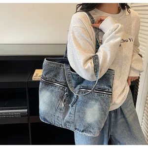 Detailed view of the dual front zipper pockets on this blue denim tote bag