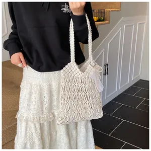 Detail der weißen Häkeltasche mit zartem Spitzenbesatz und eleganten Perlenanhängern