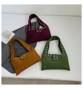 Three suede underarm bags in burgundy, yellow, and green with metal grommet details