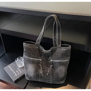 Detail of vintage black washed denim tote bag with dual metal zippers and long tassels