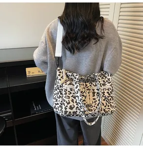 Detail of leopard print tote bag showing multi-zipper pockets and wide shoulder strap