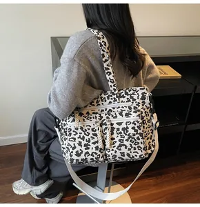 Close-up of leopard print tote bag featuring multiple zipper pockets and wide crossbody strap