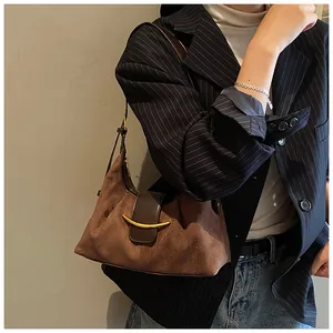 Détail du sac à bandoulière en daim marron avec boucle en métal doré élégante