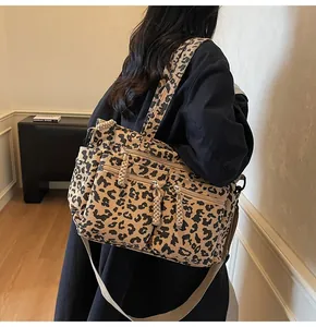 Detail of leopard print corduroy tote showing metal zippers and textured multi-pocket design