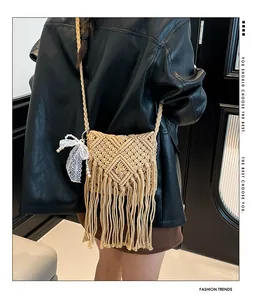 Detail of bohemian woven crossbody bag with long fringes and pearl bow charm