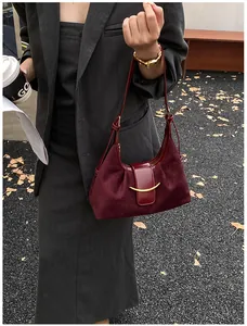 Détail d'un sac à main bordeaux en daim et cuir avec boucle métallique dorée élégante
