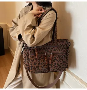 Close-up of leopard print corduroy tote with multiple zipper pockets and braided pulls
