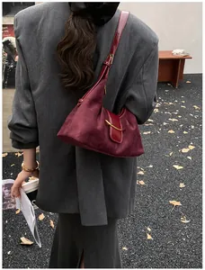 Détail du sac bandoulière en daim bordeaux avec boucle en métal doré pour femme en automne