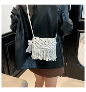 Macro shot of boho white cotton macrame crossbody bag featuring long fringes and tassel details