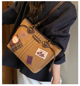 Gros plan d'un cabas vintage en daim marron avec écussons brodés et coutures fines