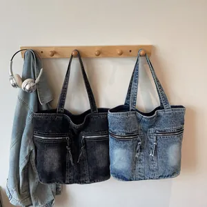 Minimalist denim tote bag with double front zippers and drawstring in blue and charcoal
